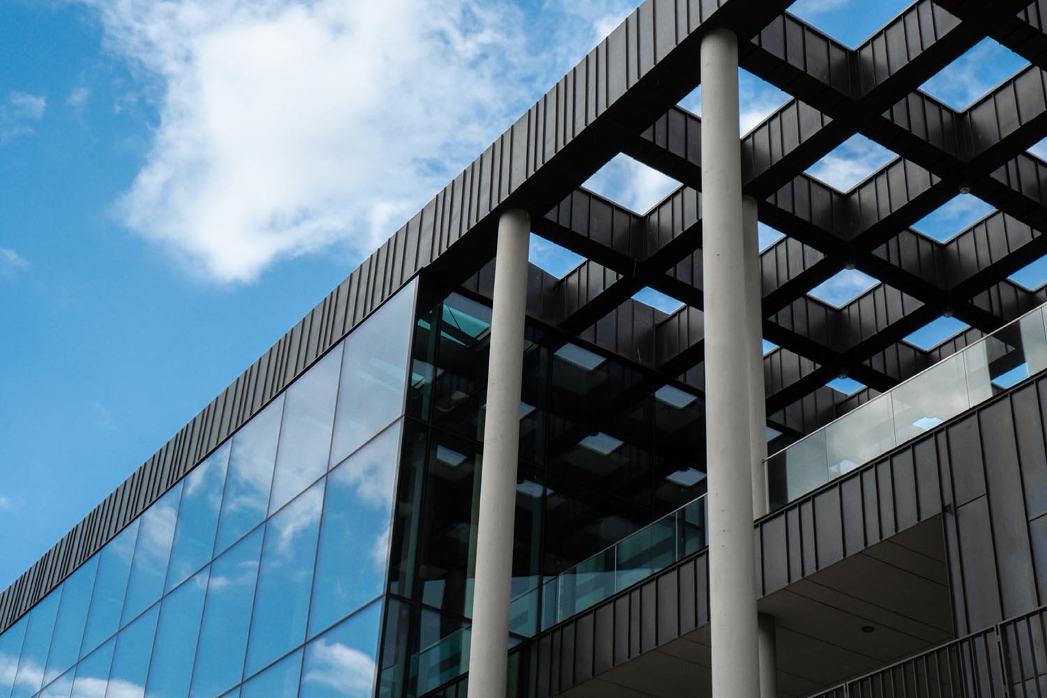 Modern office building exterior with glass facade on clear sky background. Transparent glass wall of office building with reflection of clouds. Element of facade of modern European building Commercial office buildings. Abstract modern business architecture